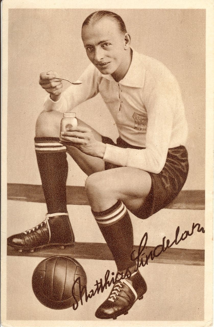 Photo d'époque de Matthias Sindelar, posant en train de manger sur un banc, ballon aux pieds